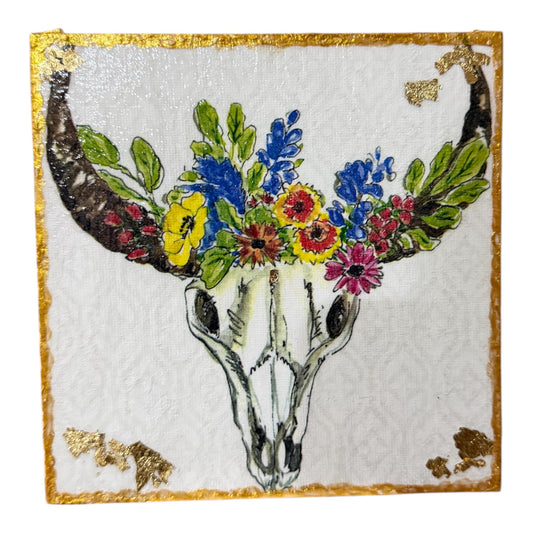 Decorative piece with a deer skull and colorful flowers on a white background with gold accents.