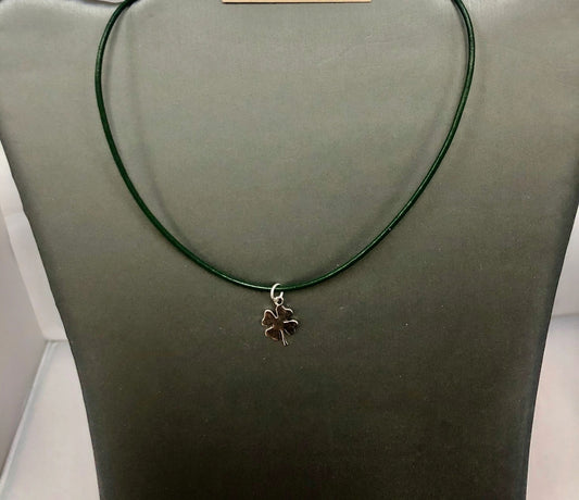 A green leather cord necklace with a silver clover shamrock pendant on display mannequin.
