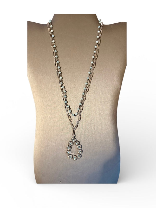 Silver necklace with a pendant on a mannequin bust against a white background