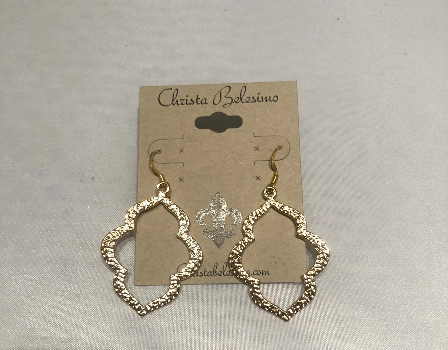 Gold tone quatrefoil earrings displayed on a card with the brand name 'Christina Balzini'.