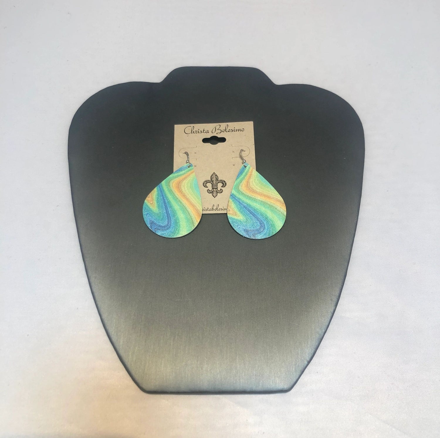 A pair of vegan green swirl earrings displayed on a silver earring hook, packaged on a card with the brand name 'Charlotte'.