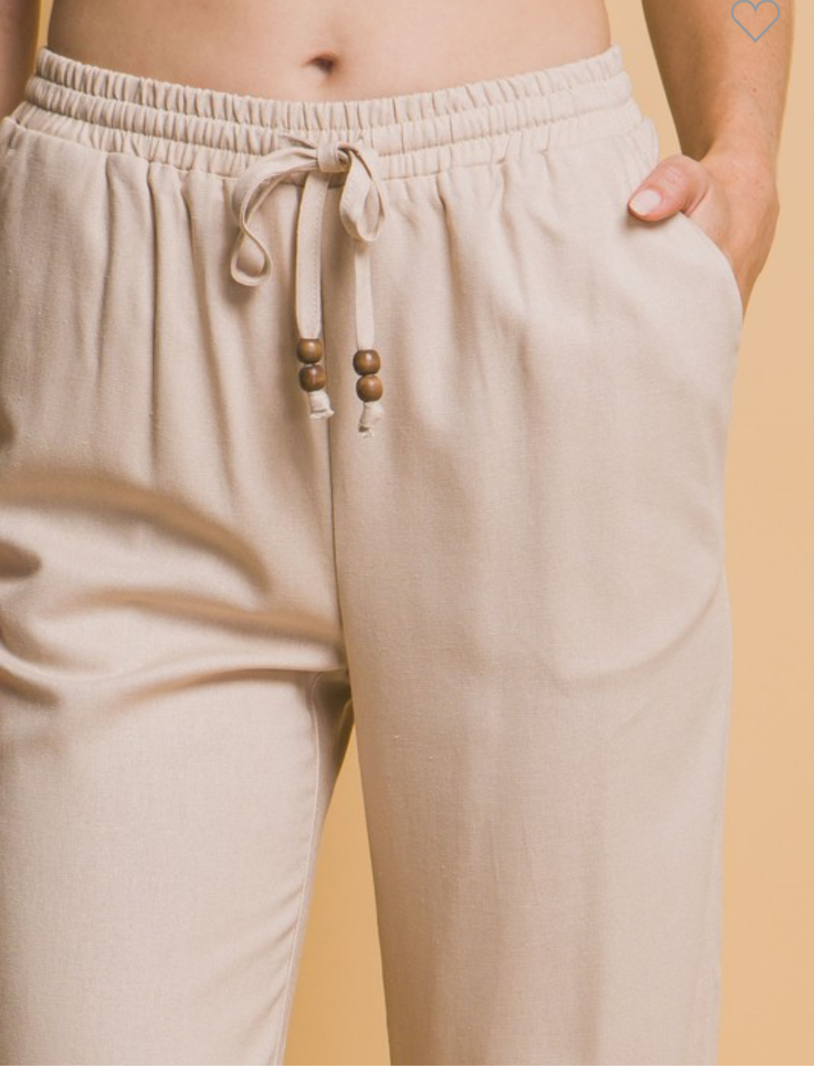 Close-up of beige linen pants with a functional drawstring waistband.