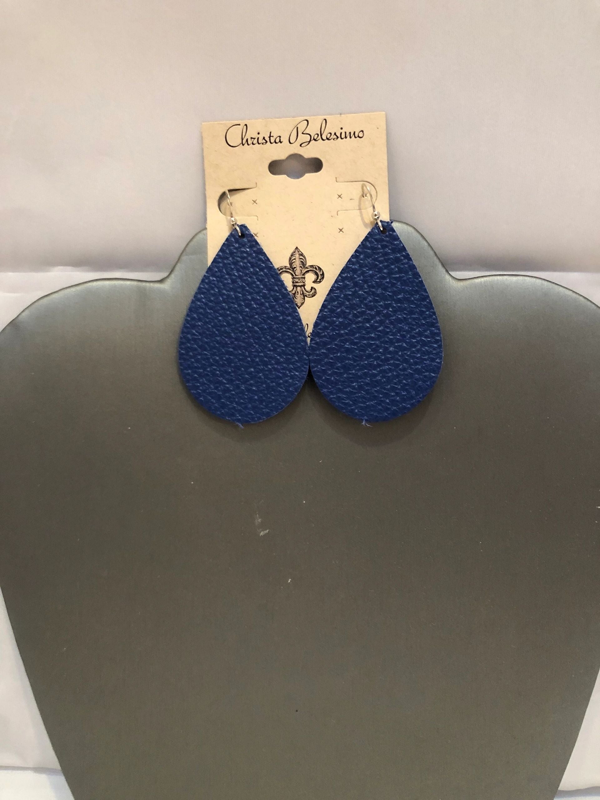 A pair of navy blue leather earrings displayed on a silver-colored earring stand with the brand name 'Charlotte Bella' tagged on the top.
