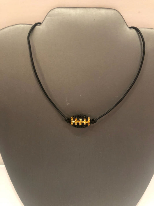A black leather cord necklace with a gold-colored football pendant, displayed on a mannequin bust.