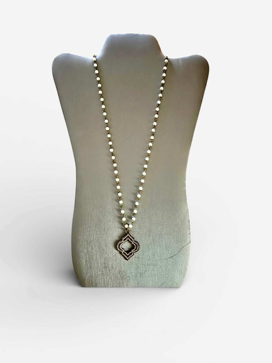 Necklace with a decorative pendant on a mannequin bust against a light gray background