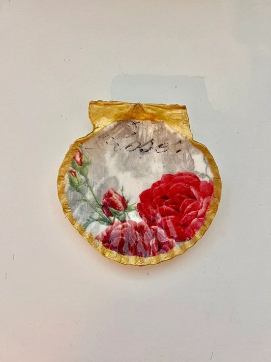A 5 inch scallop shell with red roses trimmed in gold, intended as a trinket dish.