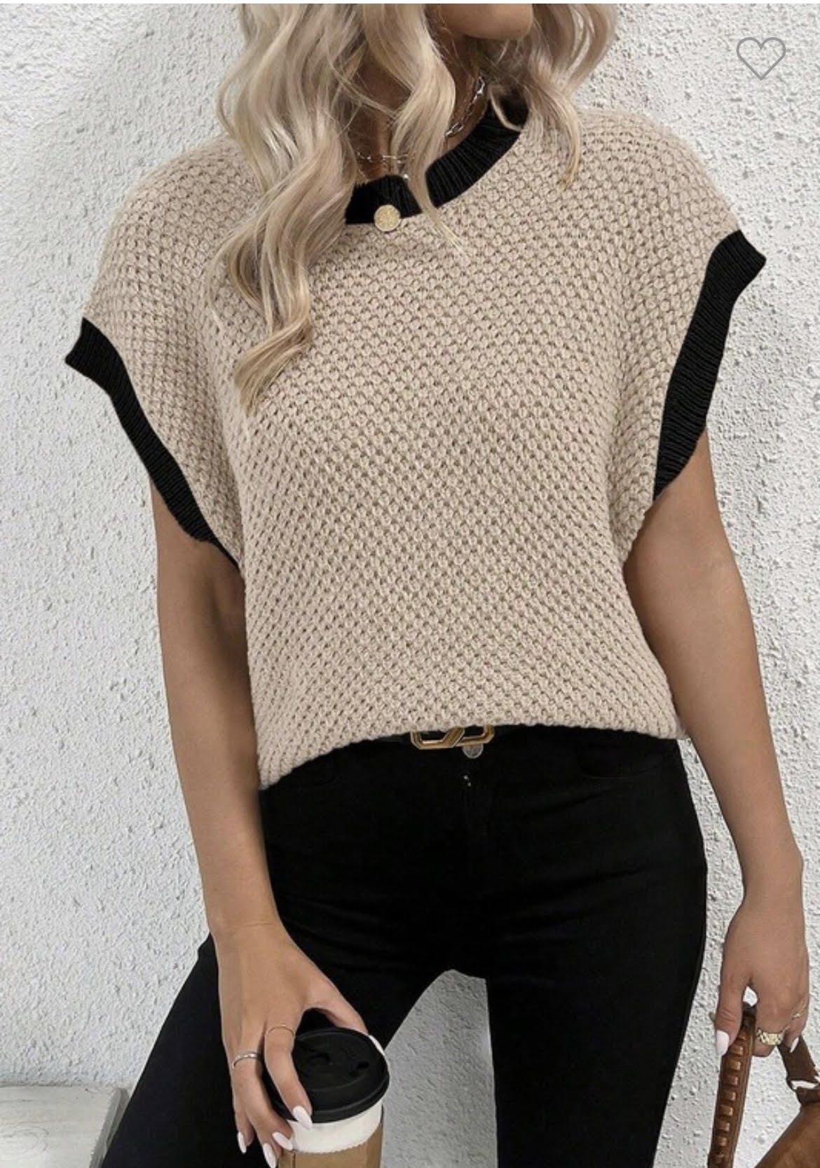 Woman wearing a beige batwing sleeve sweater top with black contrast trim