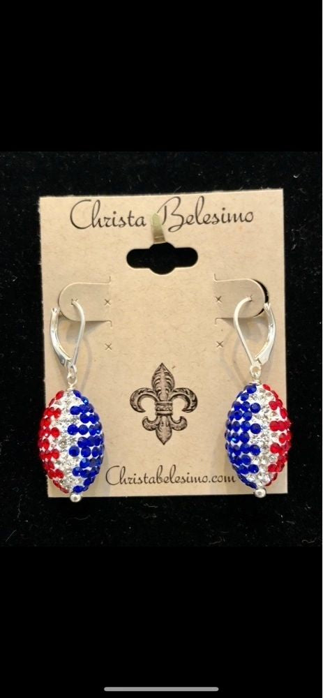 A pair of sterling silver football earrings with red, white, and blue pave crystals, featuring a lever back hook, packaged on a card with 'Christina Balsini' branded at the top.