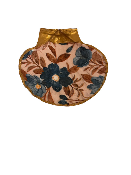 A scallop shell with pink and blue floral pattern, used as a trinket holder.