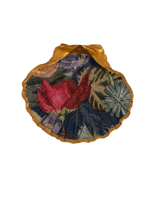 A decorative scallop shell with a rose design on a blue background with gold trim.