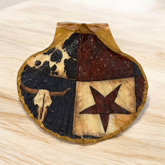 A decorative Western scallop shell with painted Texas star and cow head motifs.